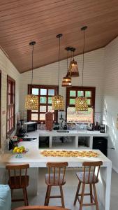 a kitchen with a white counter and two chairs at Vila do Sussurro - Casinha Céu in Triunfo