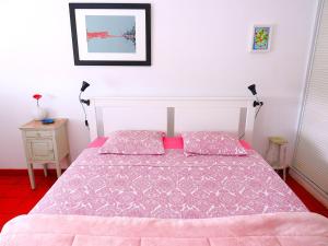 a bedroom with a bed with a pink comforter at Al-Madan in Almada