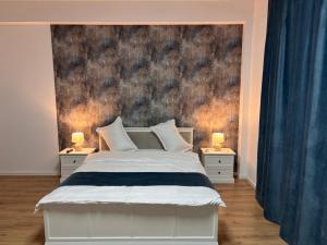 a bedroom with a white bed and two nightstands with lamps at Stadium Side Rooms in Craiova