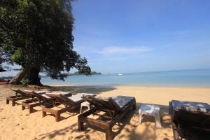 una fila de mesas y sillas de madera en una playa en Heaven Beach Resort & Art, en Ko Phayam