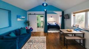 a blue living room with a couch and a bedroom at Skye Blue Bothy in Teangue