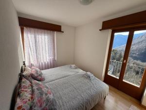 a bedroom with a bed and a large window at La Pergola in Auressio +1 photo