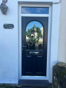 a black door with a window and a plant at Glan Morfa in Morfa Nefyn