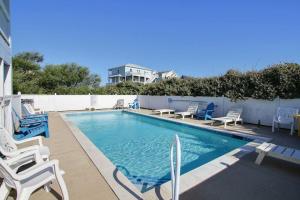 a swimming pool with chairs and a house in the background at Dune Deck in Corolla