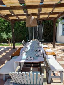 a long dining table with chairs under a wooden pergola at Villa El Carmen in Sanlúcar la Mayor