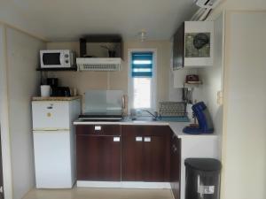a small kitchen with a sink and a refrigerator at Le mobil home bleu ! Camping Naturiste in Montalivet-les-Bains +26 photos