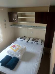 a white bed with two pillows on top of it at Le mobil home bleu ! Camping Naturiste in Montalivet-les-Bains