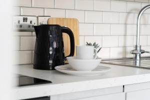 a white counter top with a coffee pot and a cup at Jasmin Place in Luton