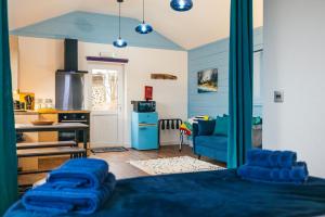 a kitchen with blue walls and a blue couch at Skye Blue Bothy in Teangue