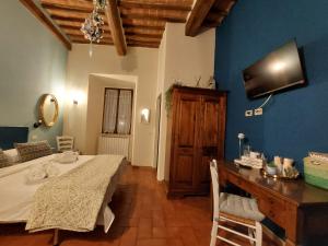 a room with a bed and a table and a television at Affittacamere Caliani in Buonconvento