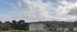 a large building in a field with trees in the background at Roseville in Limerick