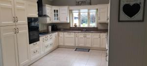 a white kitchen with white cabinets and a window at Roseville in Limerick