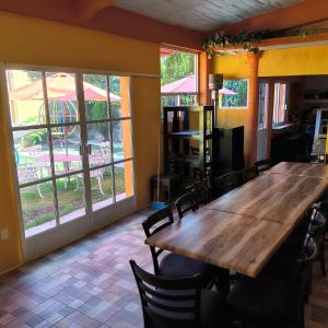 a dining room with a wooden table and some windows at Casa Granada Jilotepec in Jilotepec