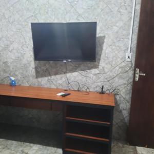 a desk with a television on a stone wall at Apartamento confortável em Cuiabá in Cuiabá