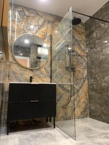 a bathroom with a shower with a mirror and a sink at Mazury Apartamenty wodne tarasy Blue - Ruś in Ruś