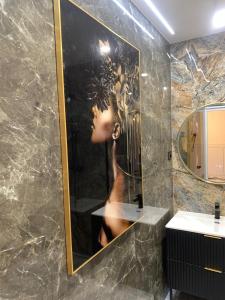 a bathroom with a picture of a woman in a mirror at Mazury Apartamenty wodne tarasy Blue - Ruś in Ruś