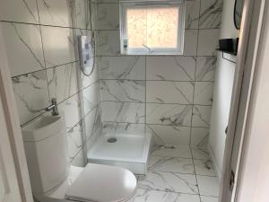 a white bathroom with a toilet and a window at Sunnyside guest house in Latchingdon and Snoreham