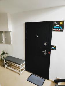 a black door in a room with a bench at Студио Нико - Царево in Tsarevo