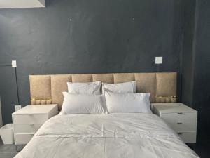 a bedroom with a large bed with two white night stands at Austra Deluxé Villa in Windhoek