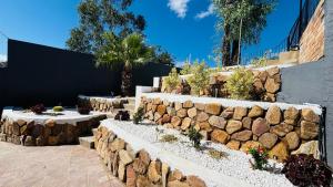 a stone retaining wall with a bunch of plants at Austra Deluxé Villa in Windhoek