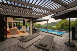 an outdoor living room with a pool and an umbrella at The Point Villas in Taupo