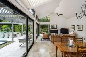 a conservatory with a dining room and living room with sliding glass doors at The Point Villas in Taupo