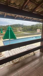 a view of a pool with a green umbrella at Espaço Villa Verde in Ibiúna
