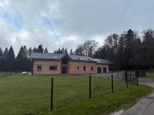 a building in a field next to a fence at Aloha House 88 in Le Val-dʼAjol