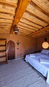 a bedroom with two beds and a wooden ceiling at Mhamid Auberge Saharaespace in Mhamid