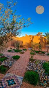 a garden with a stone walkway in front of a building at Mhamid Auberge Saharaespace in Mhamid