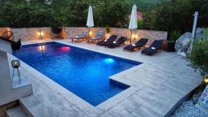 a swimming pool in a backyard with chairs and umbrellas at Villa Vilić in Vrgorac