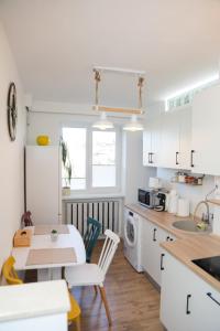 a kitchen with white cabinets and a table and a sink at Happy Place Făgăraș in Făgăraş +5 photos