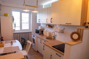 a kitchen with white cabinets and a sink and a table at Happy Place Făgăraș in Făgăraş