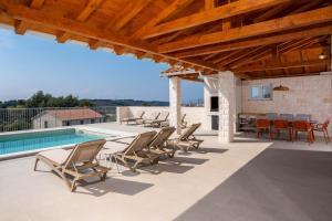a patio with chairs and a table and a swimming pool at NEW! Villa Rabella - Luxury Oasis, Island Rab in Rab