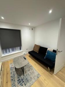 a living room with a black couch and a flat screen tv at Tranquil 3BD in Watford in Watford