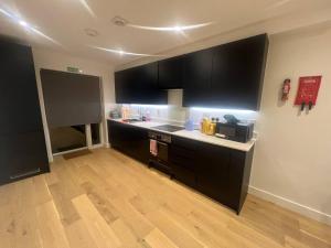 a kitchen with black cabinets and a wooden floor at Tranquil 3BD in Watford in Watford +13 photos