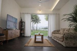 a living room with a couch and a large window at Kumarakom Homes in Kumarakom
