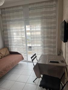 a room with a table and a bed and a window at Megalou Alexandrou in Nea Moudania
