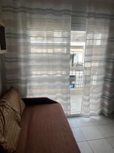 a living room with a window with curtains and a couch at Megalou Alexandrou in Nea Moudania