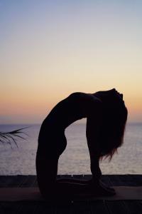 a woman doing a yoga pose in front of the ocean at Zen Townhouse - Infinity Seaview in Palaiokastro