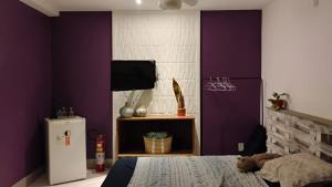 a bedroom with purple walls and a bed and a tv at Villa do Condado in Saquarema