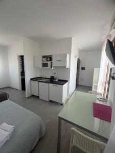 a room with a bed and a table and a kitchen at Aurasol Alghero in Alghero