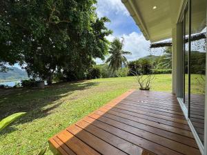 a wooden porch of a house with a field of grass at Panorama Bungalow in Tahaa +4 photos