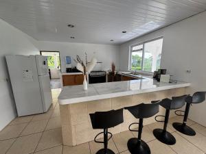 a kitchen with a counter with chairs and a refrigerator at Grand Panorama Villa in Tahaa +17 photos