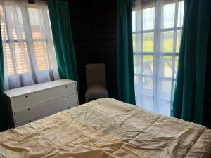 a bedroom with a bed and a dresser and two windows at La Escondida in Estación Monte