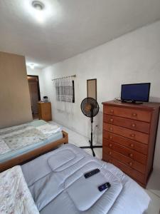 a bedroom with two beds and a dresser with a television at Flat Serrano in Miguel Pereira
