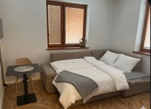a bed in a room with a table and two windows at Nido in the center in Poprad