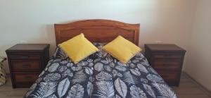 a bed with two yellow pillows and two night stands at El gran Jacarandá in Viña del Mar