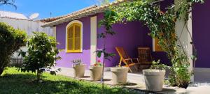 a purple house with potted plants in the yard at Villa do Condado in Saquarema