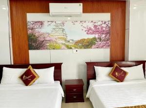 two beds in a room with a painting on the wall at Stargazer Hotel in Danang